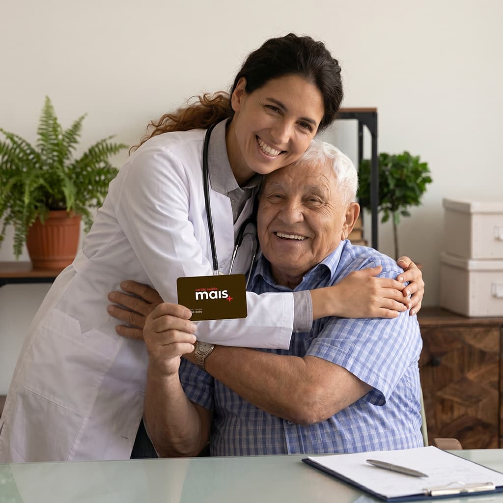 Paciente idoso sorrindo ao lado da médica, mostrando seu cartão saúde